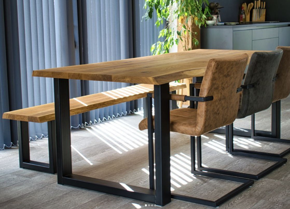 Eiken eettafel met live edge en zwart stalen onderstel, met bijpassende bank, in een lichte eetkamer